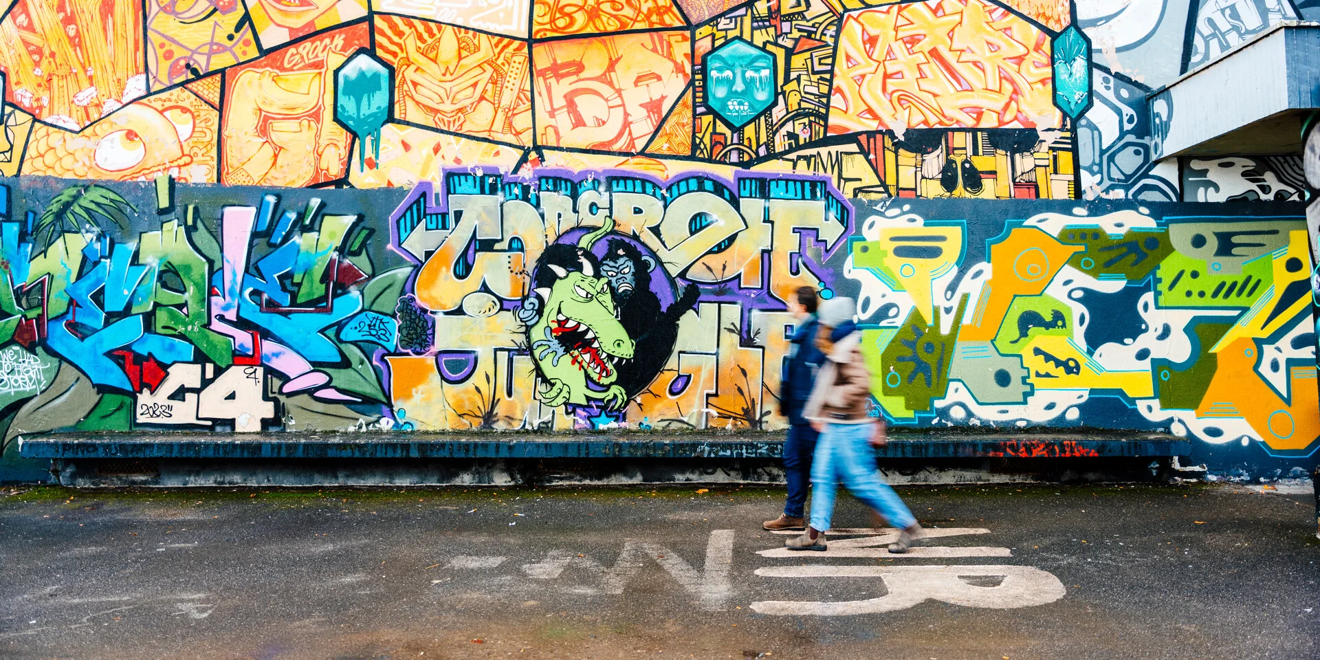 Una coppia passeggia davanti a un affresco di street art a Saint-Julien-en-Genevois