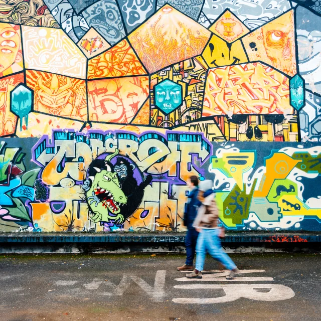 Una coppia passeggia davanti a un affresco di street art a Saint-Julien-en-Genevois